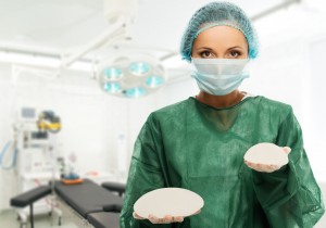 26674565 - plastic surgeon woman holding different size silicon breast implants in surgery room interior